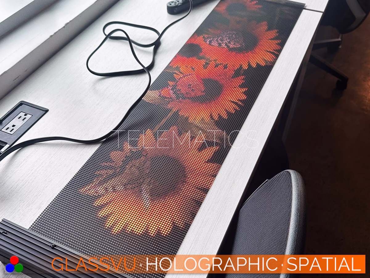 The Art Of Light · GlassVu Spatial · Telematics Canada Custom GlassVu Spatial see-through digital signage module resting on a workstation displaying high-contrast 3D floral visuals.